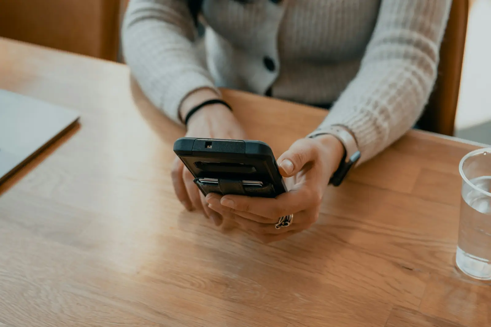 Hands holding a phone over a wooden café table