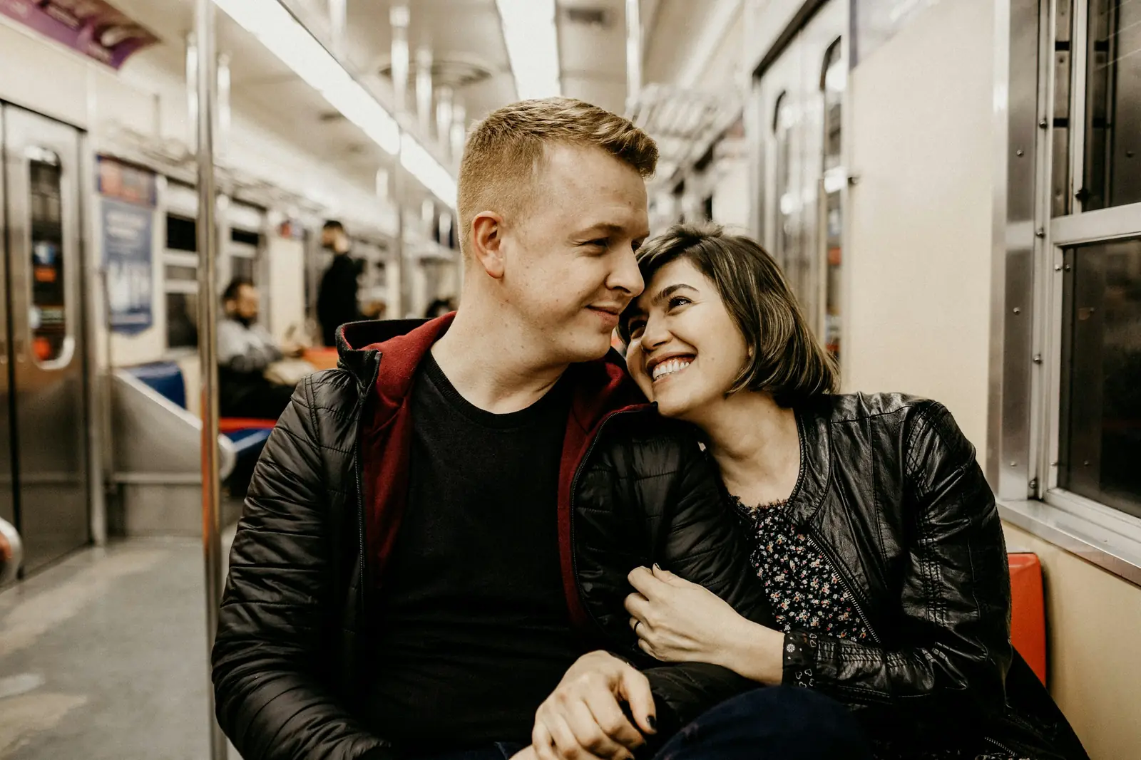 A smiling couple sitting close together on a train